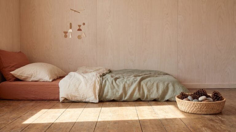 Quarto de bebê montessoriano visto do chão, com colchão baixo, móbile de madeira e luz da manhã